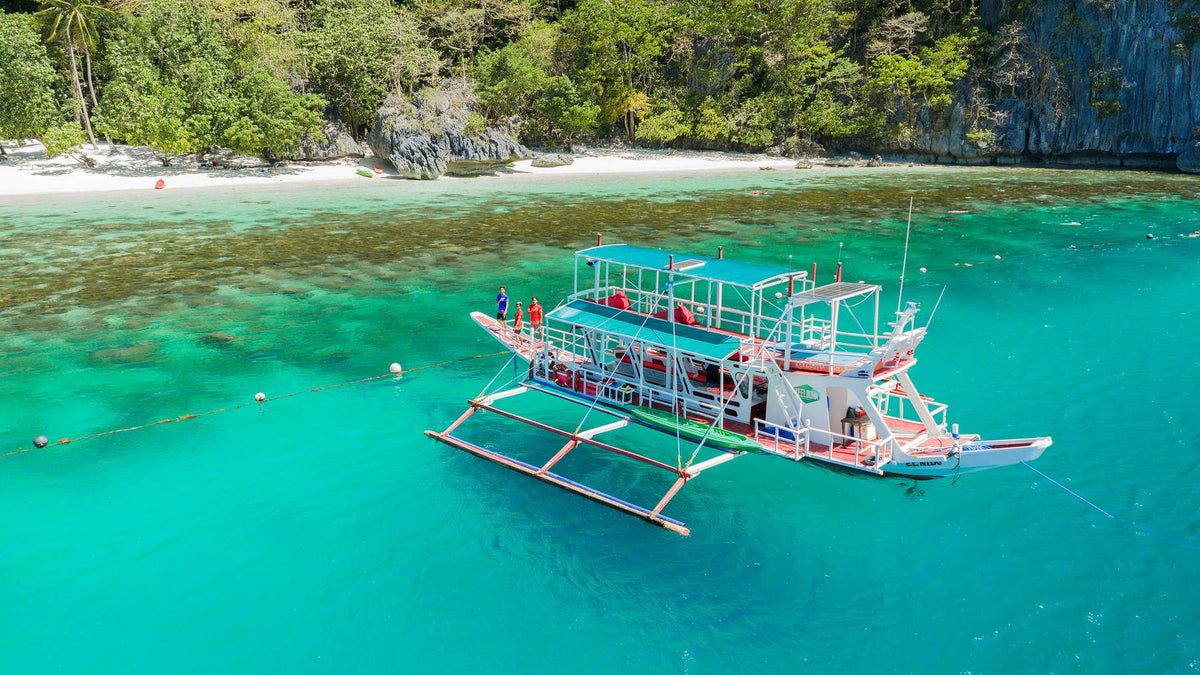 Keelooma outrigger boat with crew, deck cushions and a kayak on board, on an El Nido island hopping tour