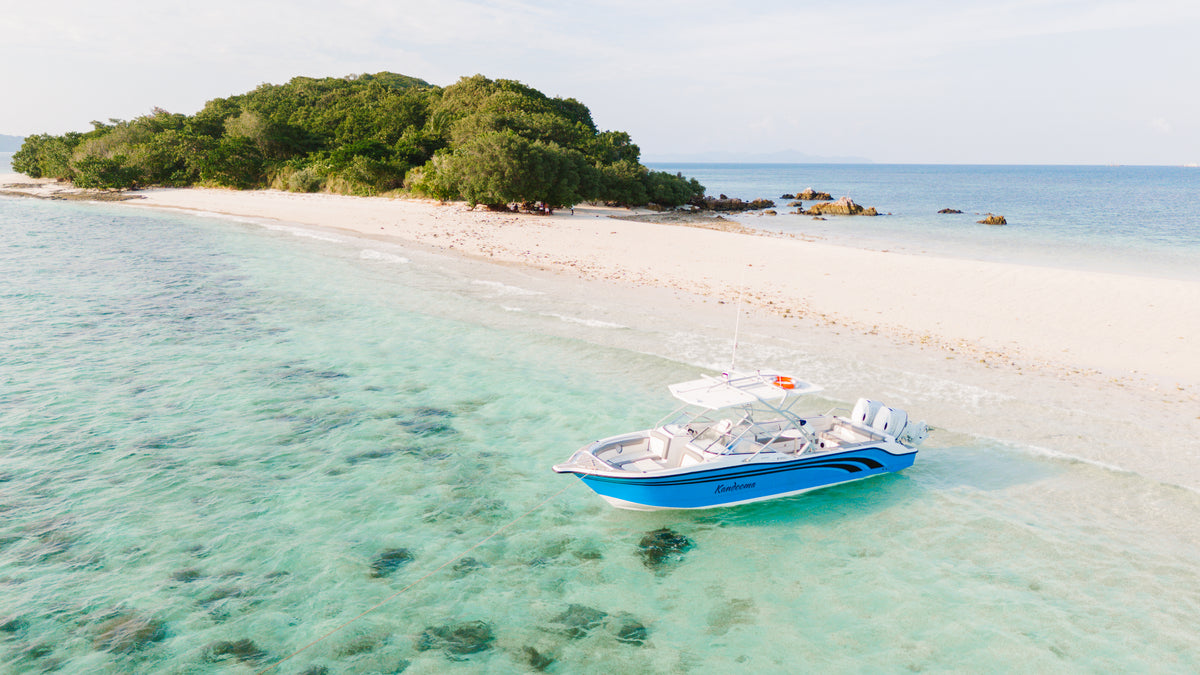 Keelooma's private speedboat Kandooma anchored in clear shallow water off an empty white sand beach in El Nido, Palawan