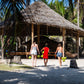 Guests and crew carrying fresh coconuts to the dining kubo at a Keelooma beach camp between El Nido and Coron, Palawan