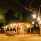 Guests at dinner under a bamboo pavilion hung with woven lanterns at a Keelooma beach camp at night, Palawan