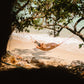 A guest resting in a woven hammock at the water's edge on a Keelooma beach camp, Palawan