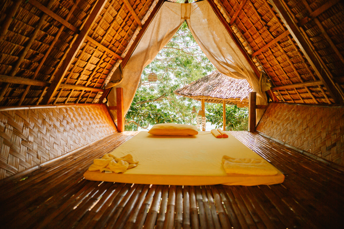 Inside a bamboo and thatch kubo at a Keelooma beach camp, with a bed facing the sea, Palawan