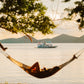 The Keelooma expedition boat anchored offshore at sunset, seen from a hammock on the beach, Palawan