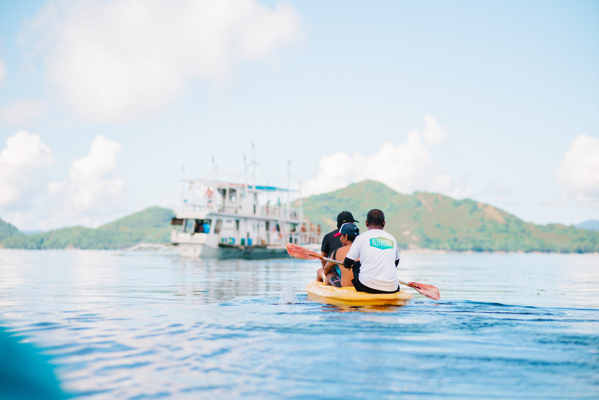 Guests kayaking out to the Keelooma expedition boat anchored off an island on the Coron to El Nido route, Palawan