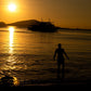 A guest wading ashore at sunset with the Keelooma expedition boat, Palawan