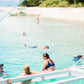 Guests snorkelling in shallow turquoise water beside the expedition boat, Coron to El Nido route, Palawan
